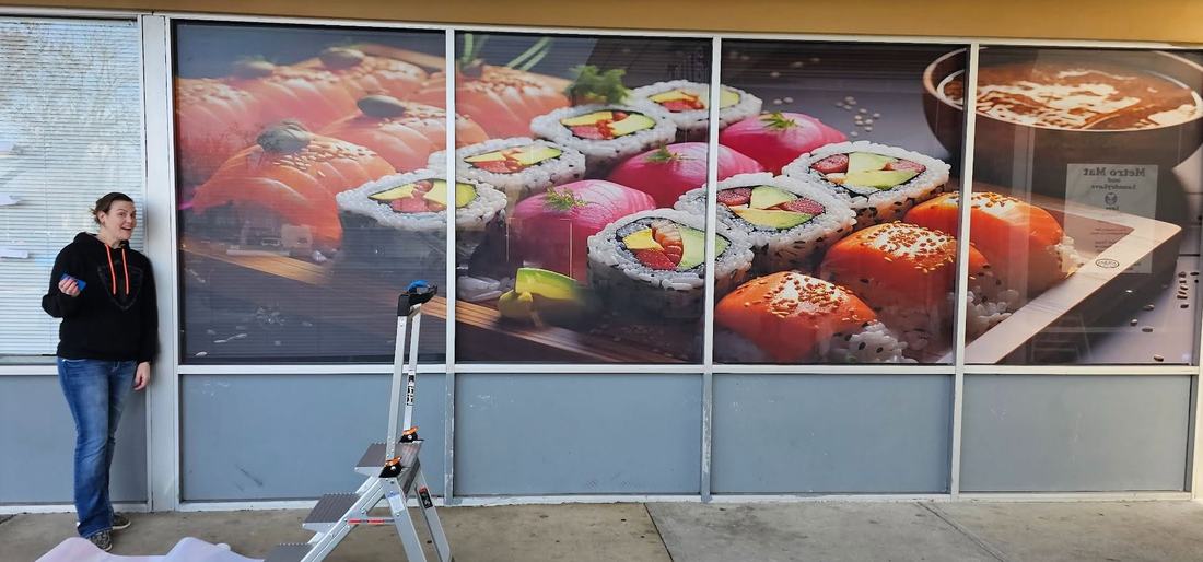 Window graphics installed by hand — Happy Valley Printing owner at work